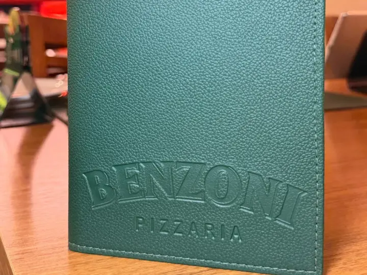 Cardápio de couro verde com o nome Benzoni Pizzaria gravado na capa
